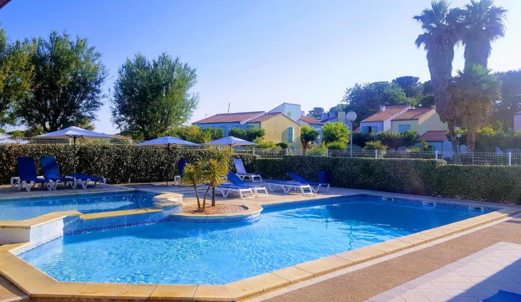 a pool with chairs and a palm tree in a yard at Village Club Thalassa in Mèze