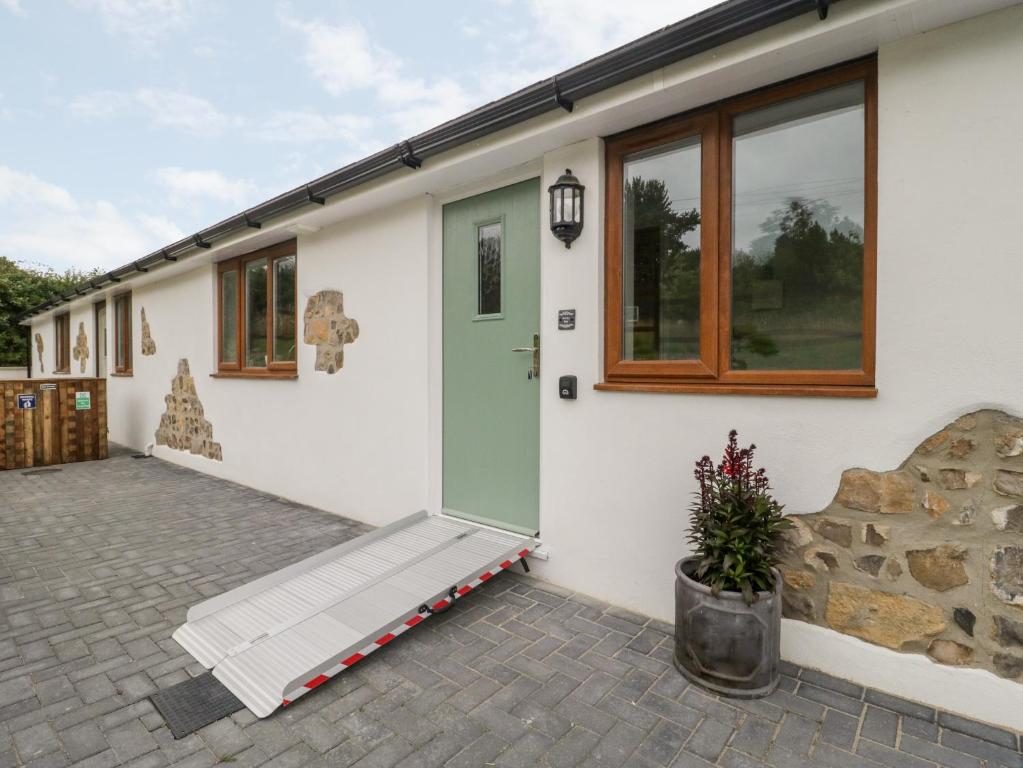 a house with a green door and a patio at Honey Bee Retreat in Axminster