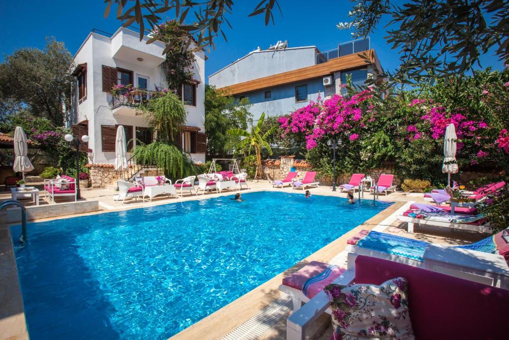 a pool in front of a building with pink flowers at Papermoon Hotel & Apartments in Kalkan