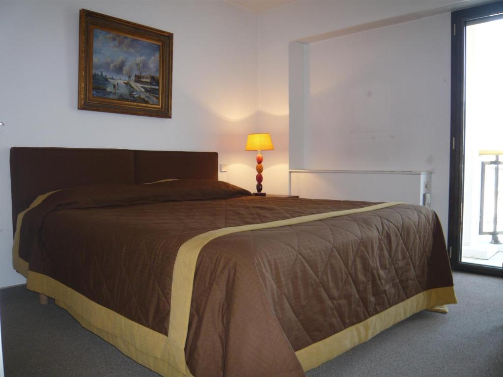 ein Schlafzimmer mit einem Bett, einer Lampe und einem Fenster in der Unterkunft Appartement Relais de la Reine Cannes Croisette in Cannes