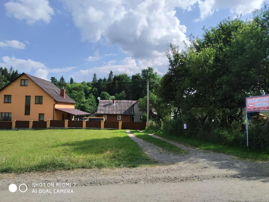 una casa al lado de un campo con un cartel en У ДЯДЬКА, en Pilipets