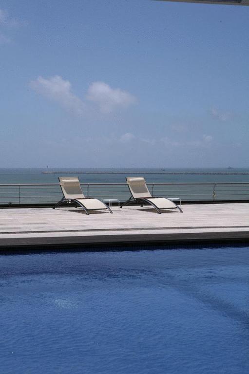 two chairs and a swimming pool next to the ocean at Mazagonia in Mazagón