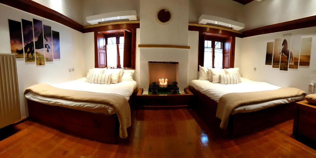 two beds in a room with a fireplace at Astraka Guesthouse I in Papingo