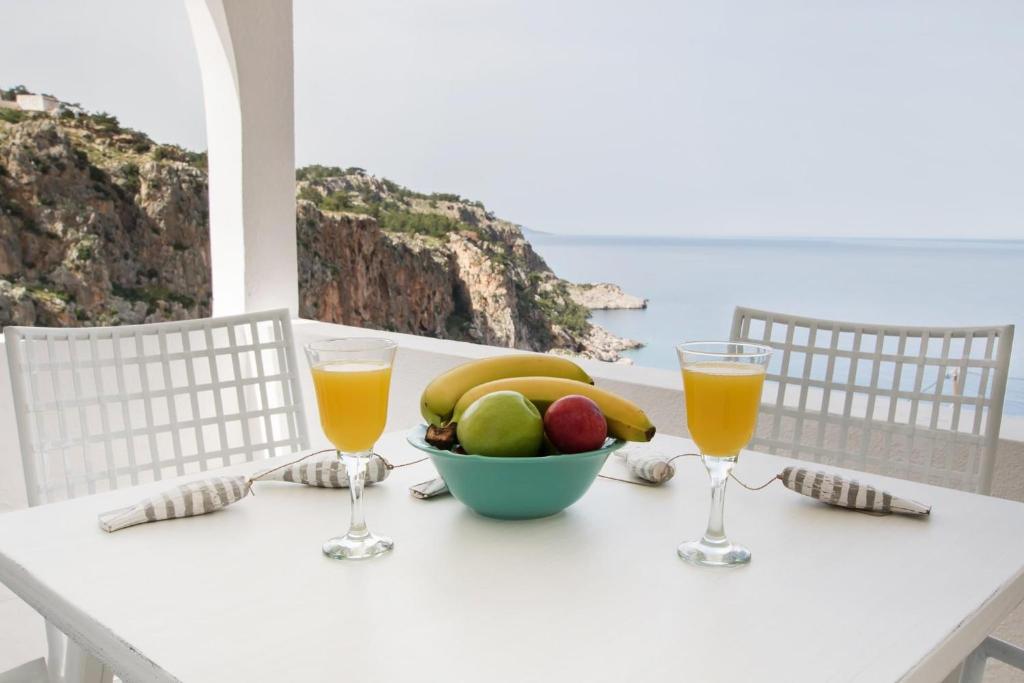 una mesa con un bol de fruta y dos vasos de zumo de naranja en Bella vista Suites en Kárpatos
