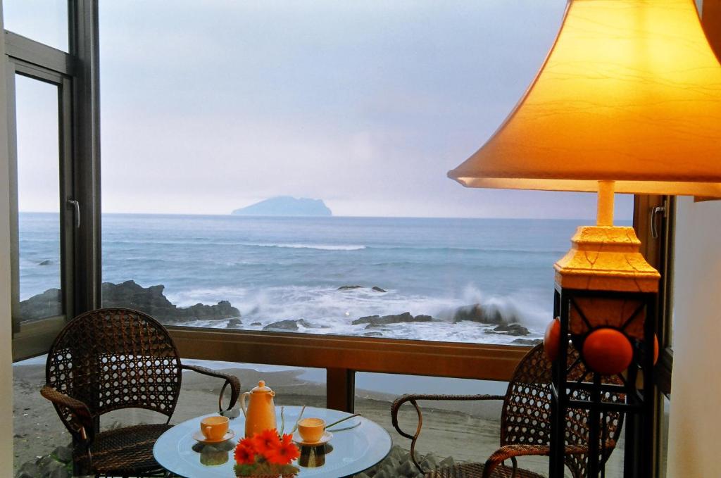 a table with a lamp and a view of the ocean at Jia Ying Beach Resort B&amp;B in Toucheng