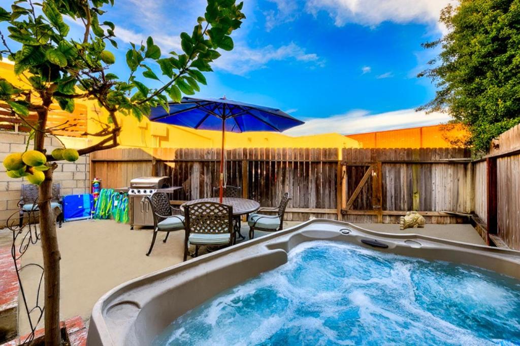 a hot tub in a backyard with a table and umbrella at Perfect Newport Beach Location With Spa I & II in Newport Beach