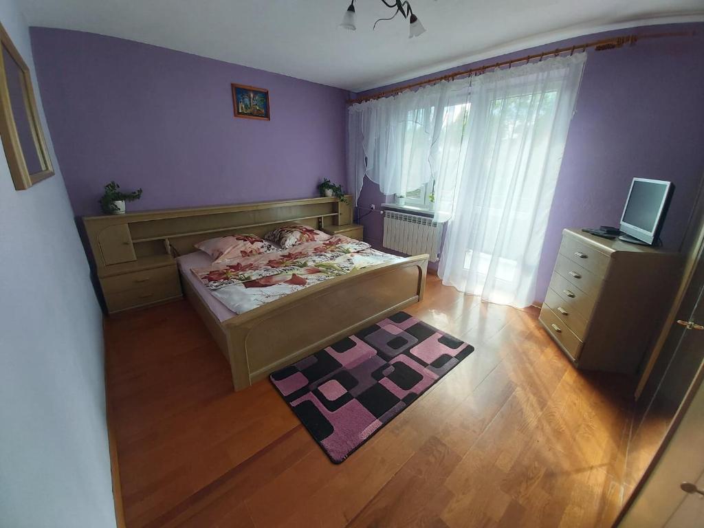 a bedroom with purple walls and a bed and a wooden floor at Apartament Berezka 667-108-706 in Polańczyk