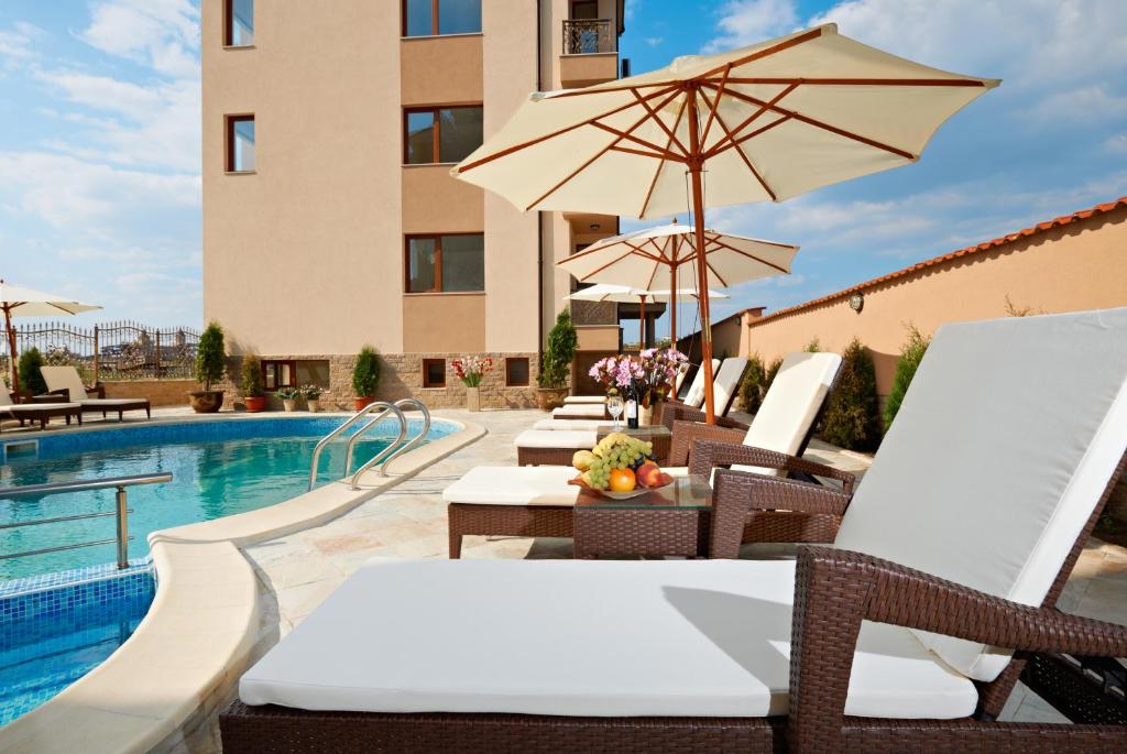 a pool with chairs and umbrellas next to a building at Stanny Court ApartHotel in Nesebar