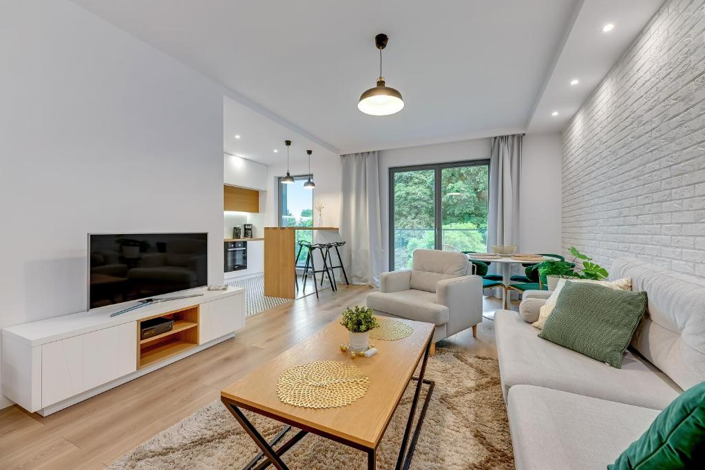 a living room with a couch and a tv and a table at Wave Apartments - Nadmorze 2 in Gdańsk