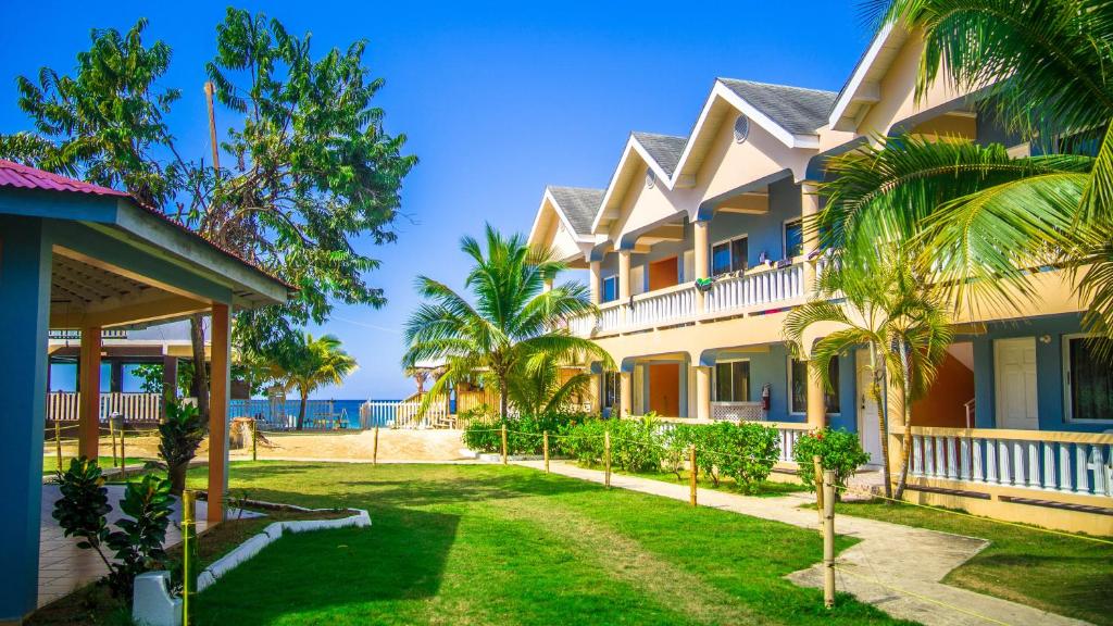 a building with palm trees and the ocean in the background at Tamboo Resort in Negril