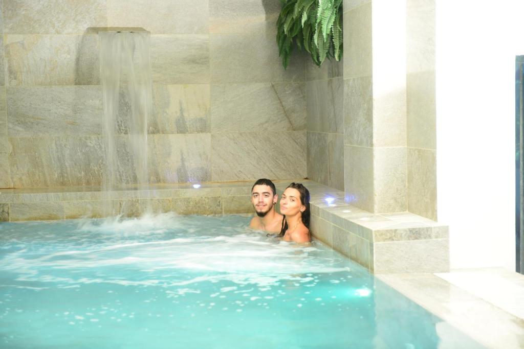 een man en vrouw in een bubbelbad met een waterval bij Hotel Mamiani & Kì-Spa Urbino in Urbino