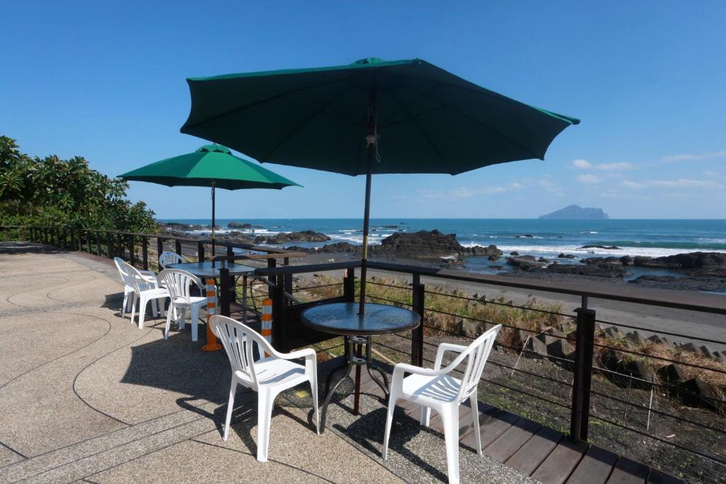 a table and chairs with an umbrella and the beach at Jia Ying Beach Resort B&amp;B in Toucheng