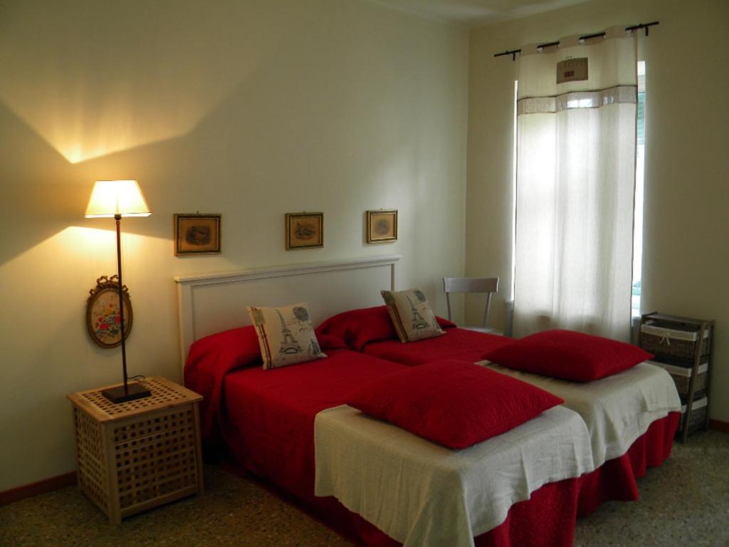 a bedroom with two beds with red sheets and a lamp at B&B Autin in Bruzolo