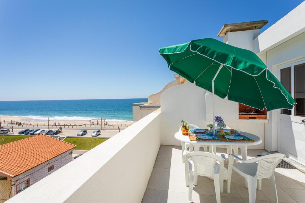 - un balcon avec une table et des chaises et la plage dans l'établissement Marinha- AL, à Praia da Vagueira