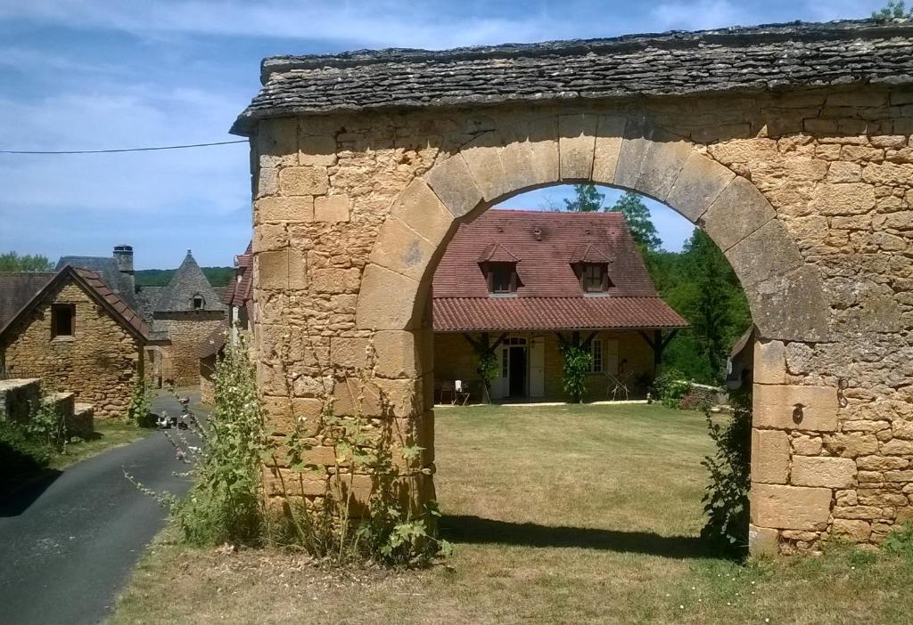 an archway in a stone building with a house at Chambre d'hôtes Lasserre in Saint-Amand-de-Coly