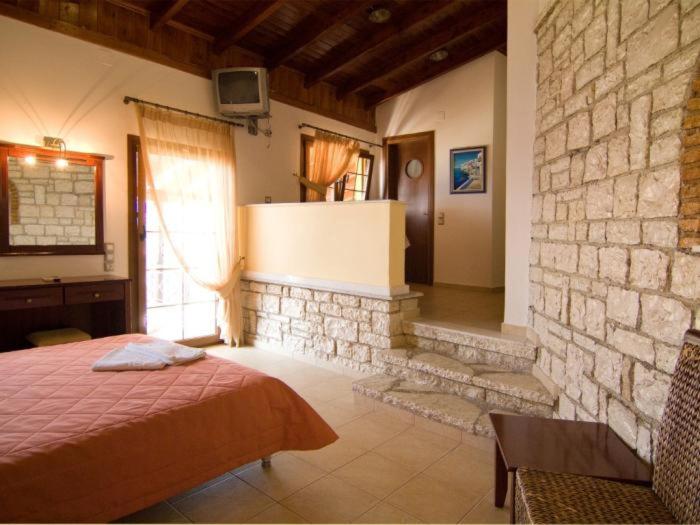 a bedroom with a bed and a stone wall at Sunset Hotel Parga in Parga