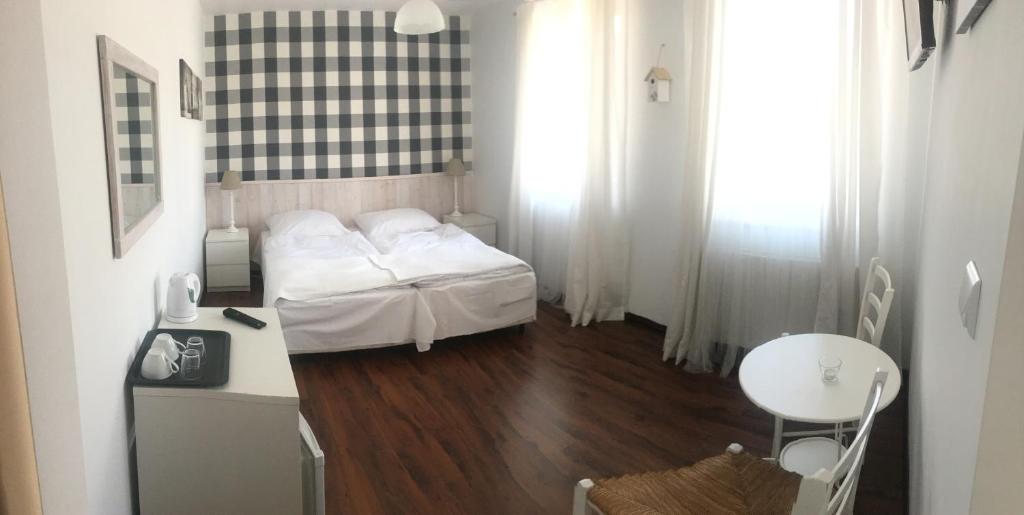 Habitación pequeña con cama, mesa y escritorio. en Pokoje Pinokio, en Darłowo