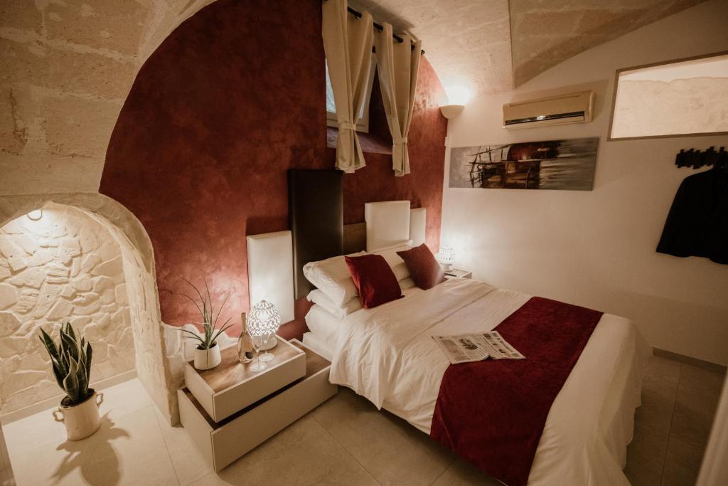 ein Schlafzimmer mit einem Bett mit einer roten Wand in der Unterkunft Pacuvius Home Suite B&B in Brindisi