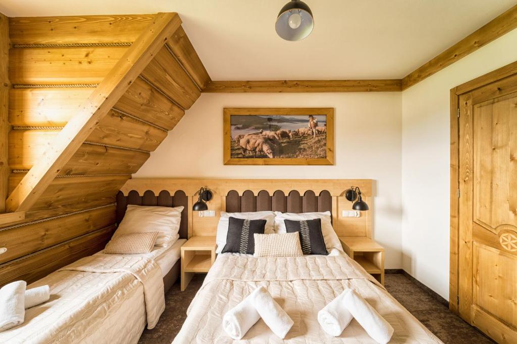 two beds in a bedroom with wooden ceilings at Karcma Hajnos Pokoje in Białka Tatrzańska