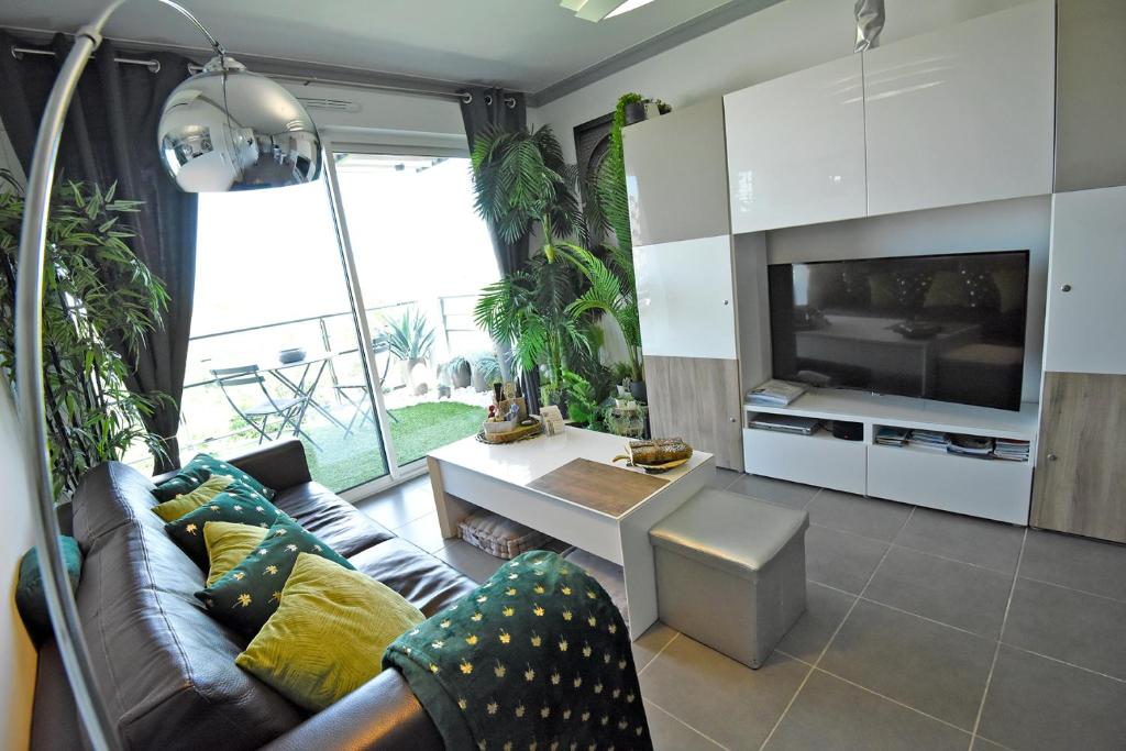 a living room with a couch and a tv at Appartement de L'Espiguette in Le Grau-du-Roi