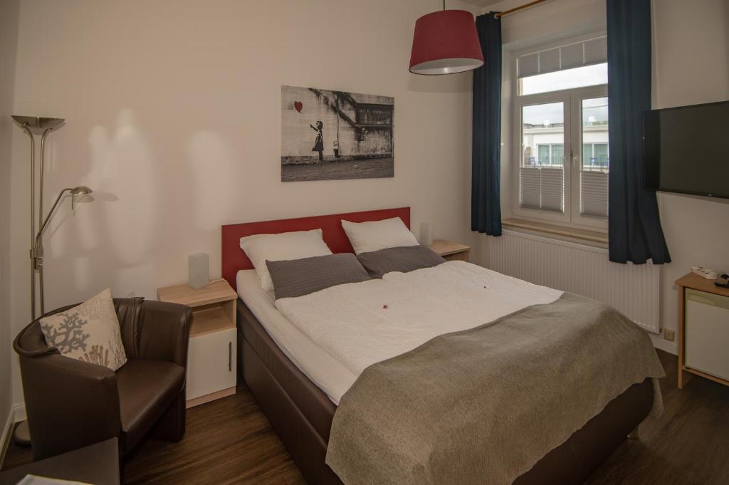 a bedroom with a bed and a chair and a window at Haus Neunaber in Norderney