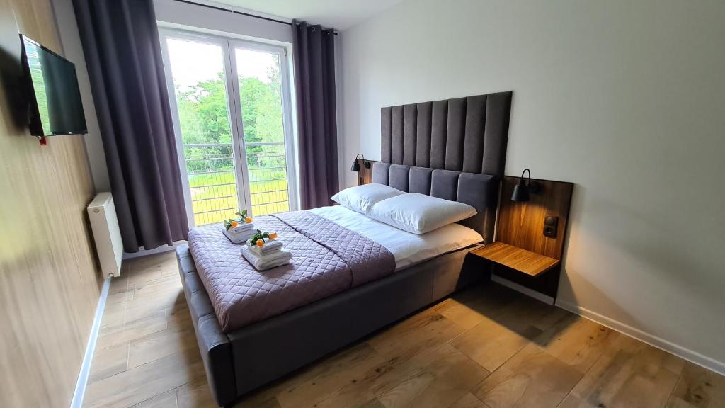 a bed in a room with a large window at Lux Apartment Loft in Polanica-Zdrój