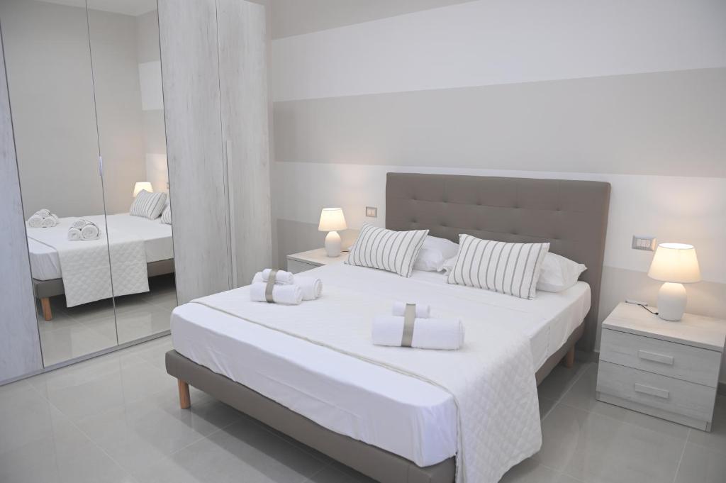 biała sypialnia z 2 łóżkami i lustrem w obiekcie STONE HOUSE Annalisa w mieście Torre Annunziata