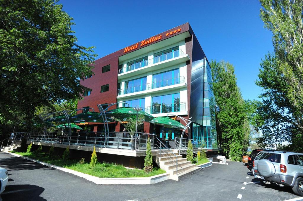 a building with a car parked in a parking lot at Hotel Zodiac in Constanţa