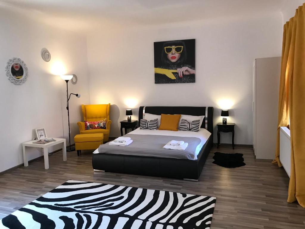 a bedroom with a bed and a yellow chair at 9 Central Residence in Braşov