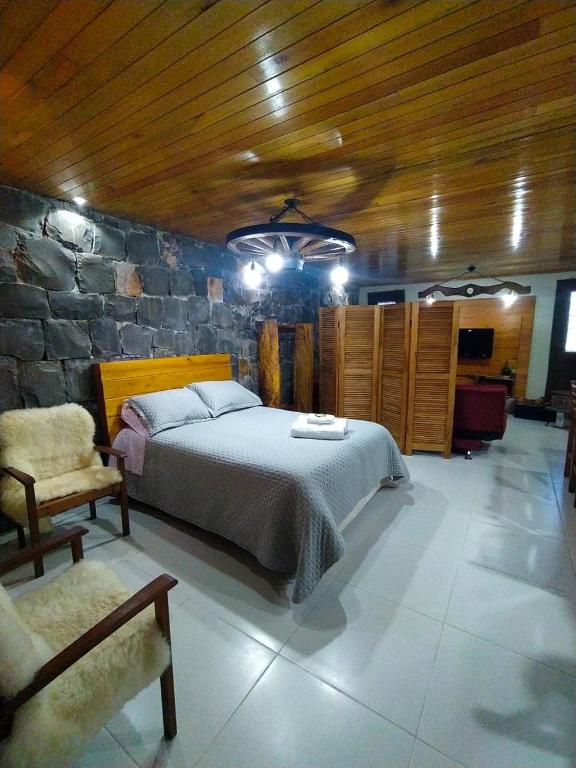 a bedroom with a bed and a stone wall at Aconchego da Serra Edícula in São Joaquim