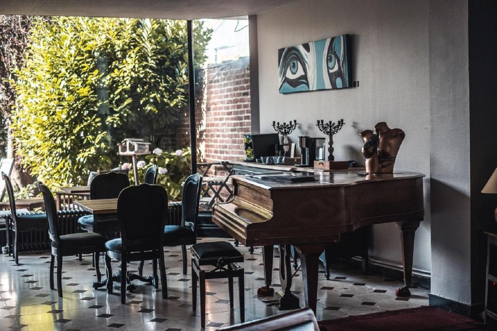 ルーベにあるLa Maison Bleue de Roubaixのピアノ、テーブル、椅子が備わる客室です。