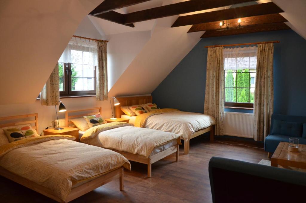a attic bedroom with two beds and a blue chair at Agroturystyka Leśny Potok in Fredropol