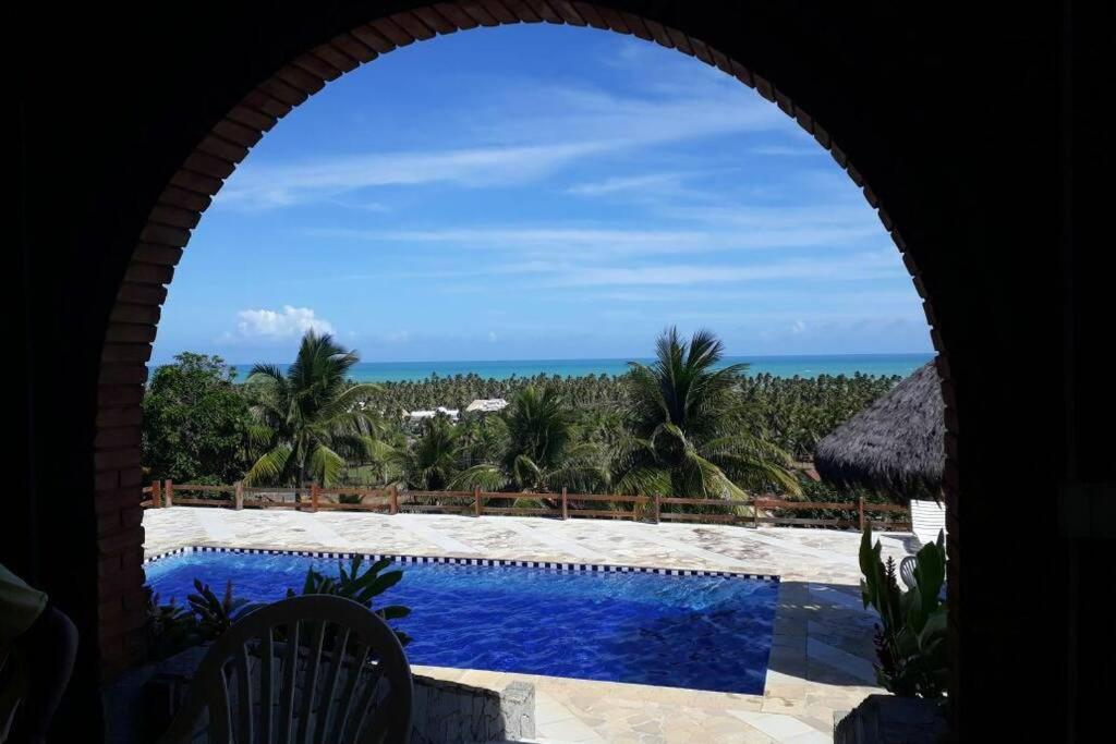 uma vista para uma piscina e para o oceano a partir de uma casa em Maravilhosa Mansão na Praia de Ipioca em Maceió