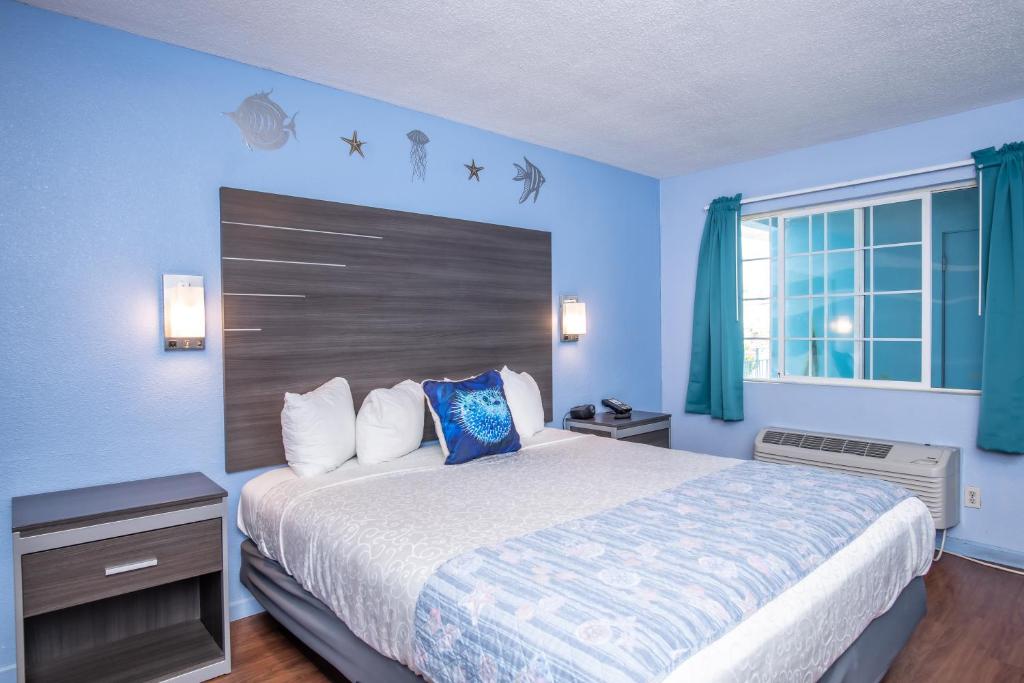 a bedroom with a bed with blue walls and a window at Aqua Breeze Inn in Santa Cruz