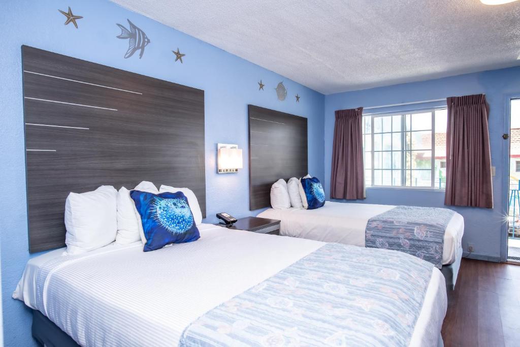 two beds in a hotel room with blue walls at Aqua Breeze Inn in Santa Cruz