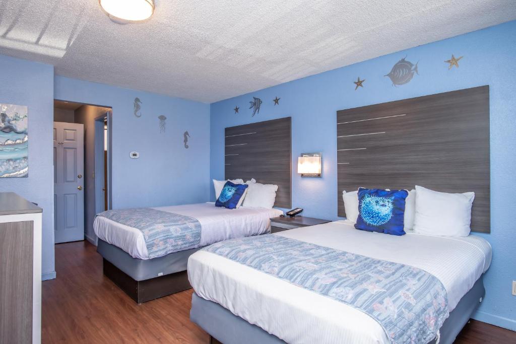 two beds in a room with blue walls at Aqua Breeze Inn in Santa Cruz