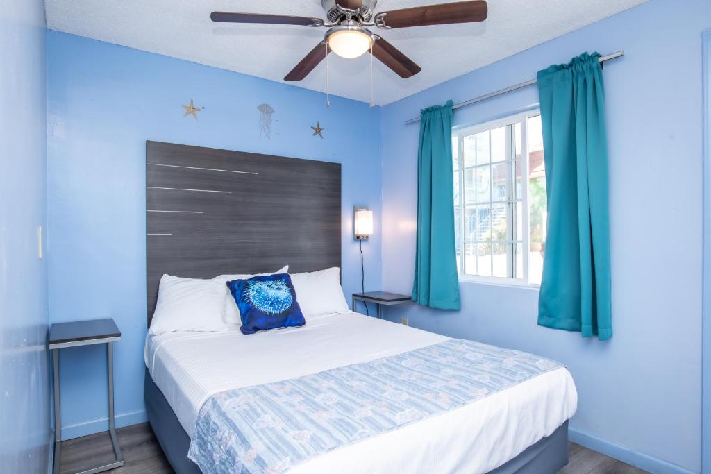 a blue bedroom with a bed and a ceiling fan at Aqua Breeze Inn in Santa Cruz