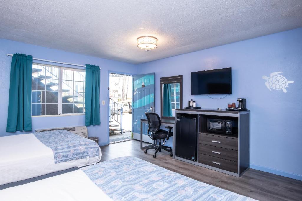a bedroom with a bed and a desk with a television at Aqua Breeze Inn in Santa Cruz
