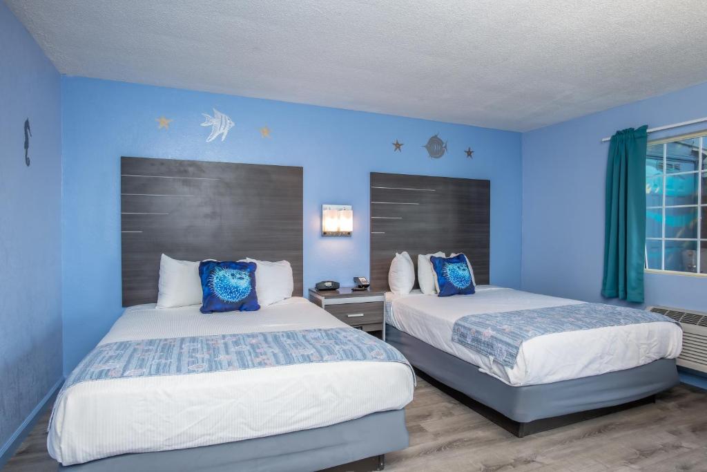 two beds in a room with blue walls at Aqua Breeze Inn in Santa Cruz
