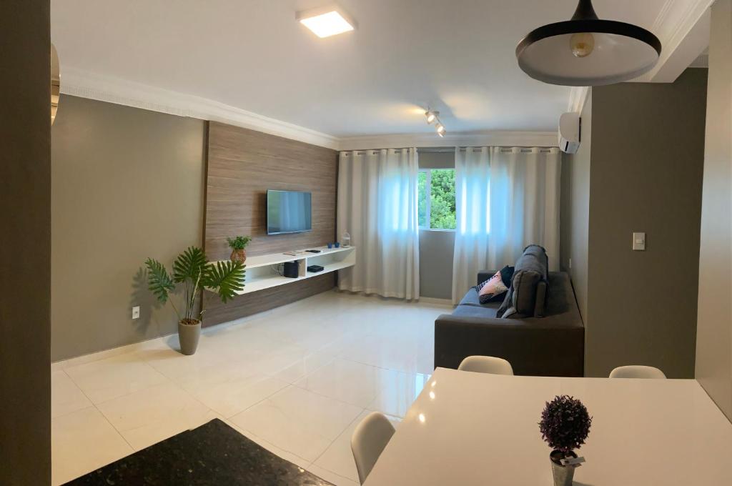 ein Wohnzimmer mit einem Sofa und einem TV in der Unterkunft Edifício Mariana Apto com 3 Quartos - Jatiúca in Maceió