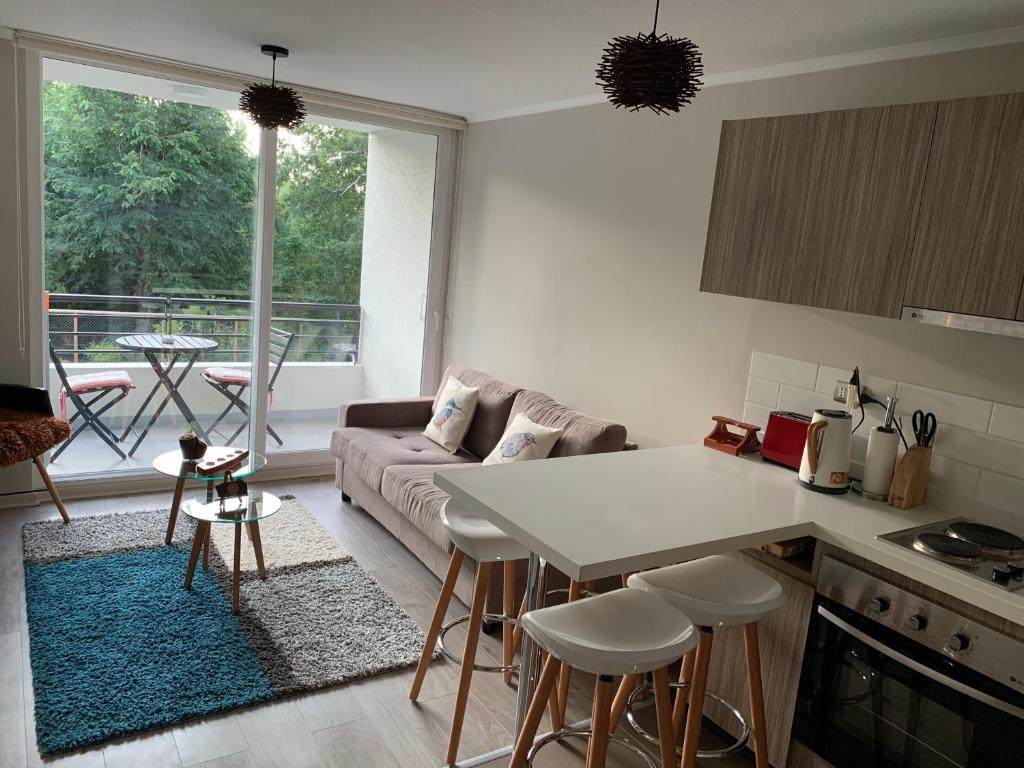 a kitchen and living room with a couch and a table at Nuevo y muy bien equipado departamento en Pucón in Pucón