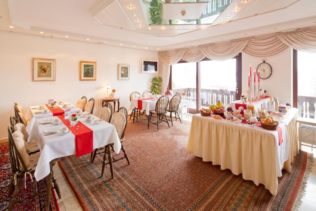 a dining room with two tables and chairs and windows at Pension Gimpel in Bad Wildungen