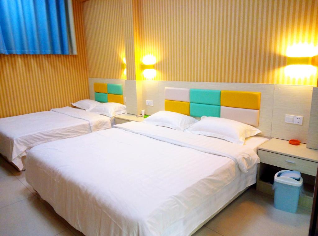 three beds in a room with yellow walls at Qufu Garden Hotel in Qufu