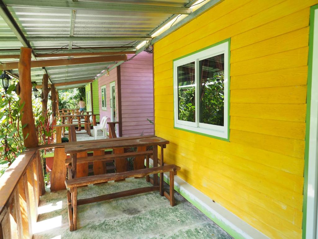 un porche con un banco en el lateral de una casa en Pattama Resort @ KeereWong, en Kiriwong
