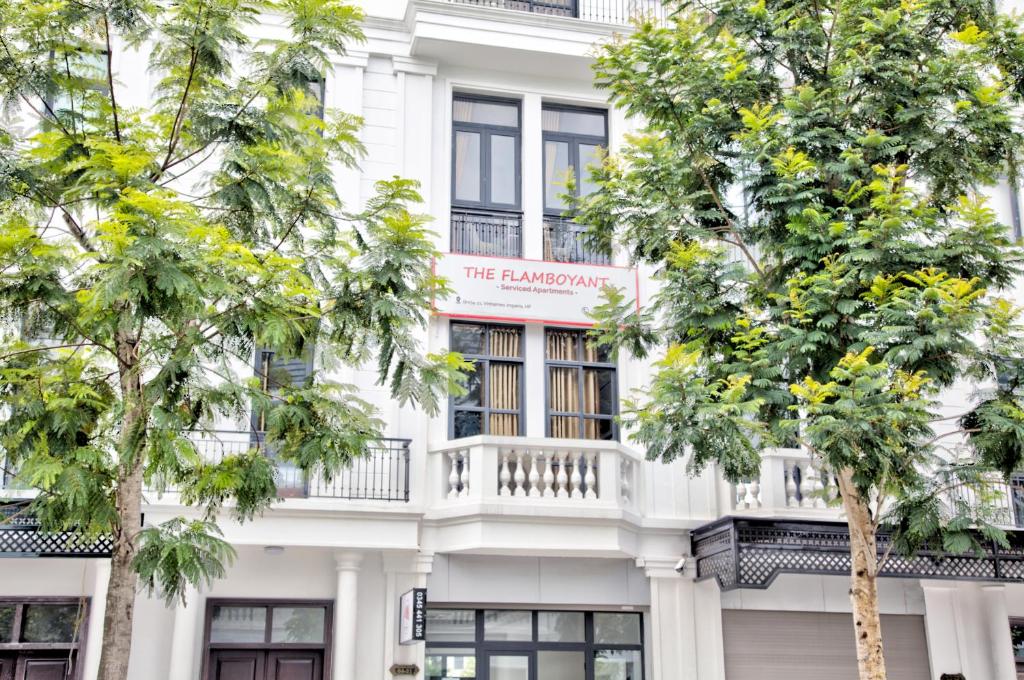 a white building with a balcony and trees at The Flamboyant #StayWork Vinhomes Imperia in Hai Phong