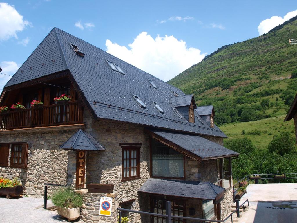 a stone house with a black roof and a balcony at Hotel Ço De Pierra in Betrén