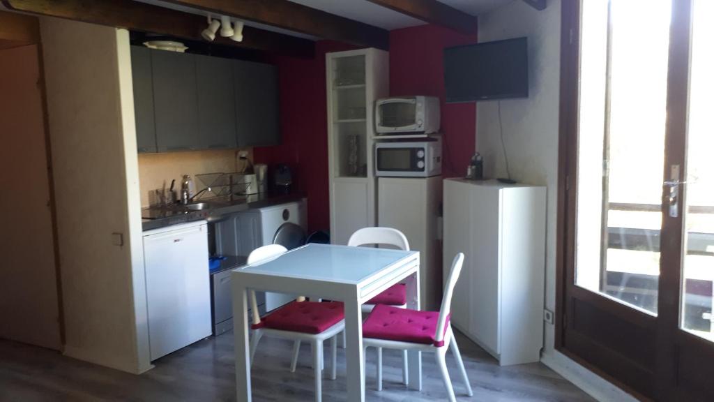 cocina con mesa, sillas y nevera en Les Bergians en Beuil