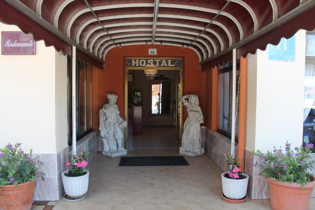 a hospital entrance with statues and flowers in pots at La Flor de Quejo in Isla