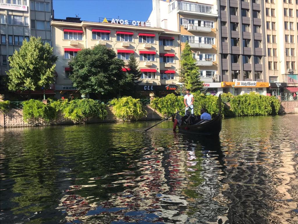 un homme dans une gondole sur une rivière avec des bâtiments dans l'établissement Atos Otel, à Eskişehir