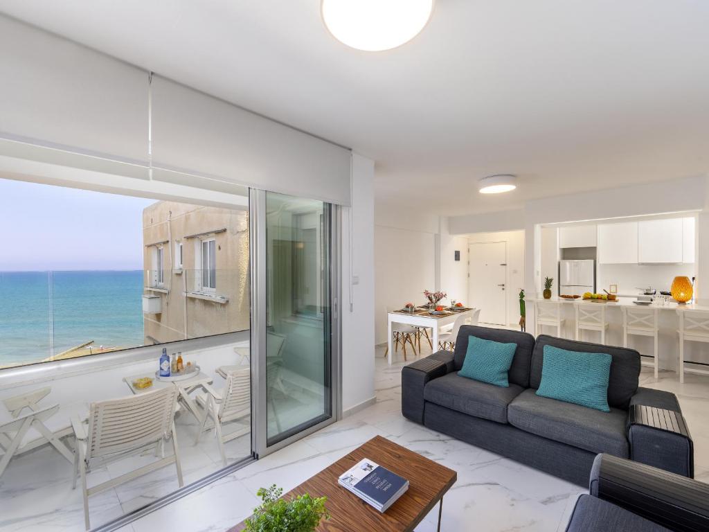 a living room with a couch and a view of the ocean at Mackenzie Leo Seafront Suite in Larnaca